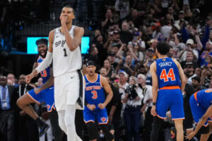 San Antonio Spurs forward Victor Wembanyama walks off the court as time expires during the second half of Game 2 of the NBA Finals basketball series as New York Knicks guard Landry Shamet (44), guard Josh Hart (3), and center Mitchell Robinson (23) celebrate, Friday, June 5, 2026, in San Antonio. (AP Photo/Eric Gay)
